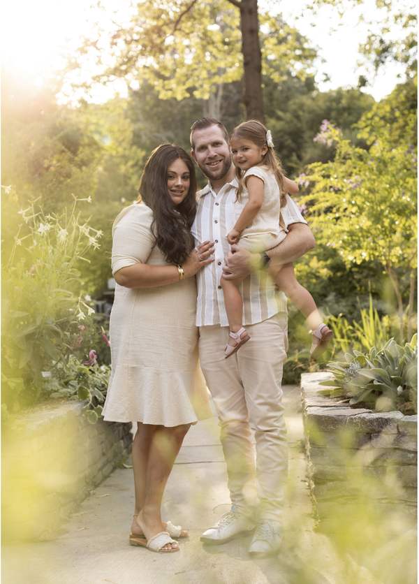 Family of three photographed in a garden at golden hour.